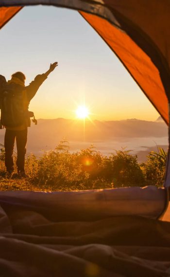 hiker-stand-at-the-camping-front-orange-tent-and-backpack-in-the-mountains-2-scaled
